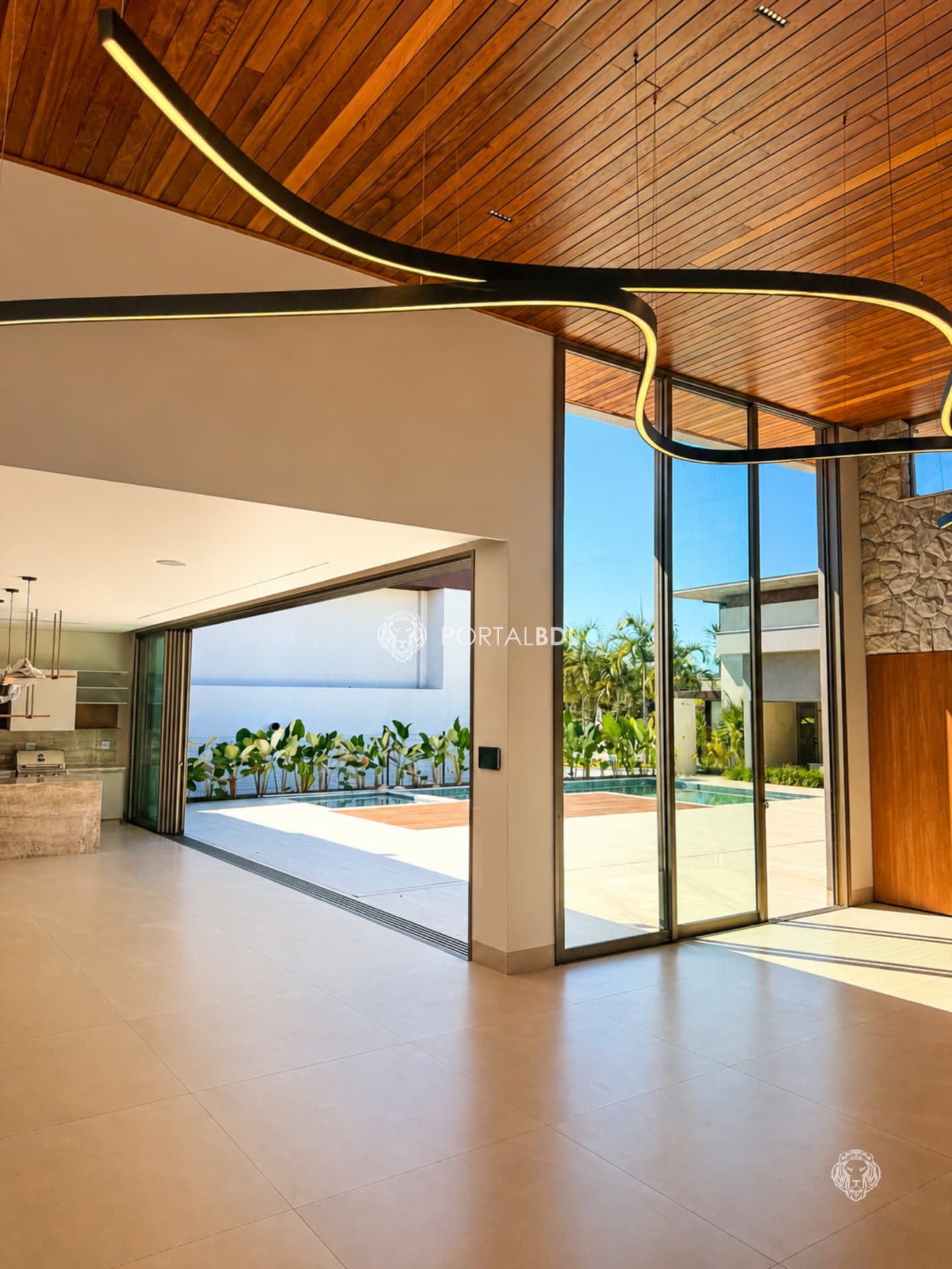 Living com forro de madeira curvo, luminária linear e vista para a piscina